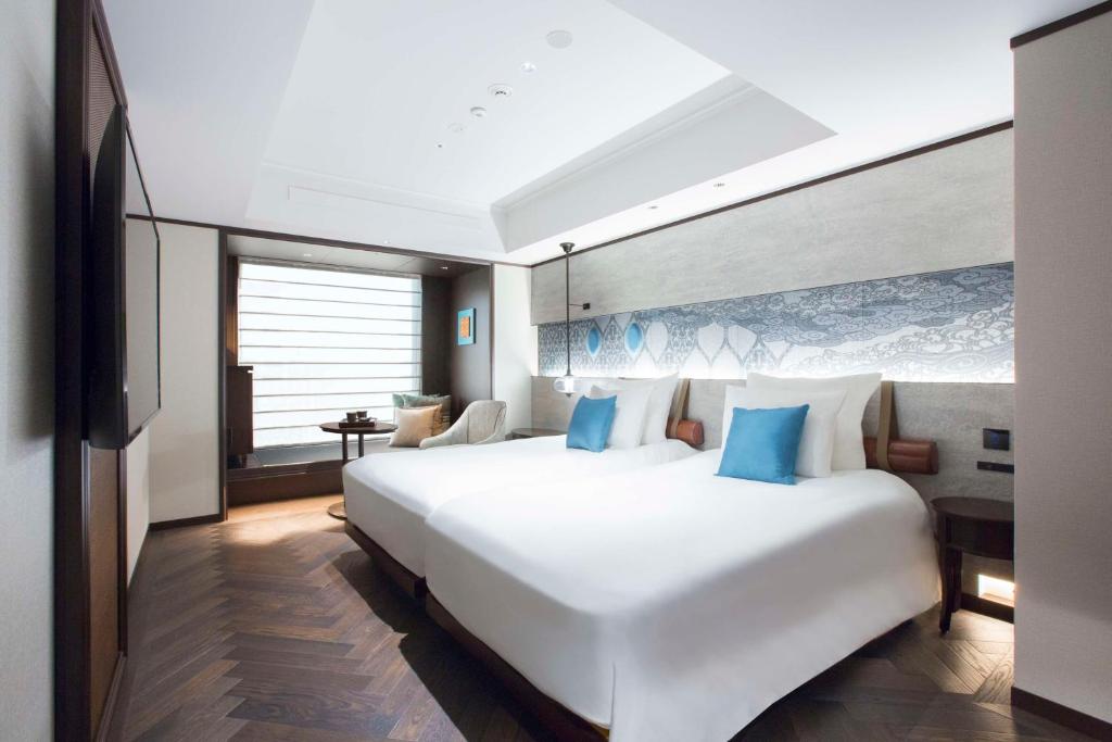 a bedroom with a large white bed with blue pillows at Dhawa Yura Kyoto - Banyan Group in Kyoto
