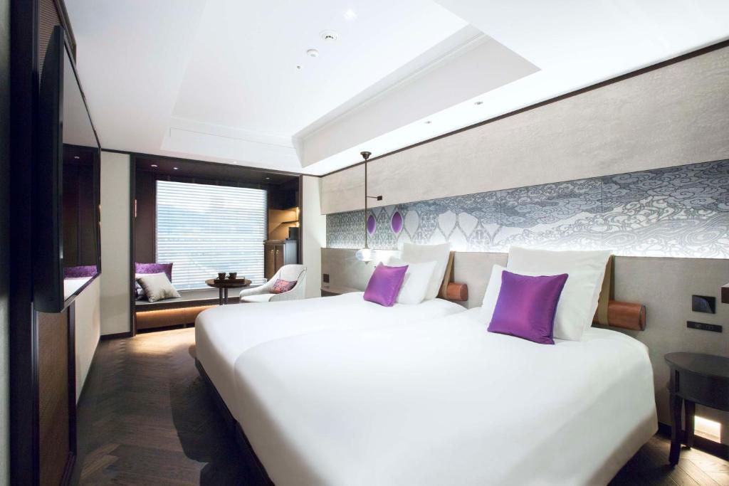 a bedroom with a large white bed with purple pillows at Dhawa Yura Kyoto - Banyan Group in Kyoto