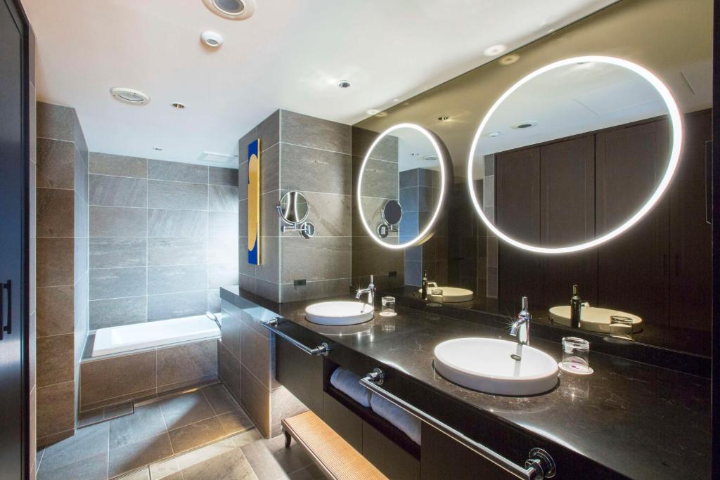 a bathroom with two sinks and two mirrors at Dhawa Yura Kyoto - Banyan Group in Kyoto