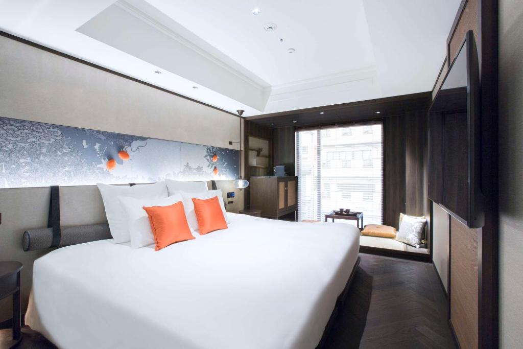 a bedroom with a large white bed with orange pillows at Dhawa Yura Kyoto - Banyan Group in Kyoto
