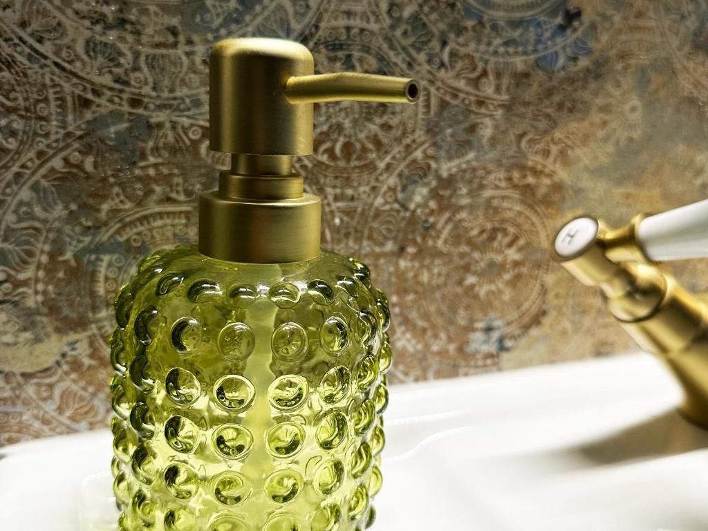 a green glass bottle sitting on top of a sink at The Cabin Near Stansted Airport in Little Hallingbury