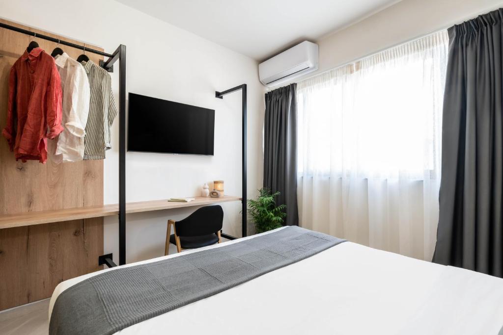 a bedroom with a bed and a desk and a window at KOYO Athens in Athens