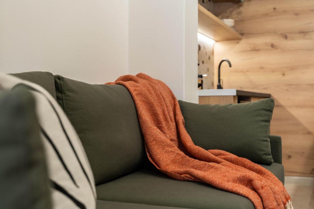 an orange blanket sitting on top of a green couch at KOYO Athens in Athens