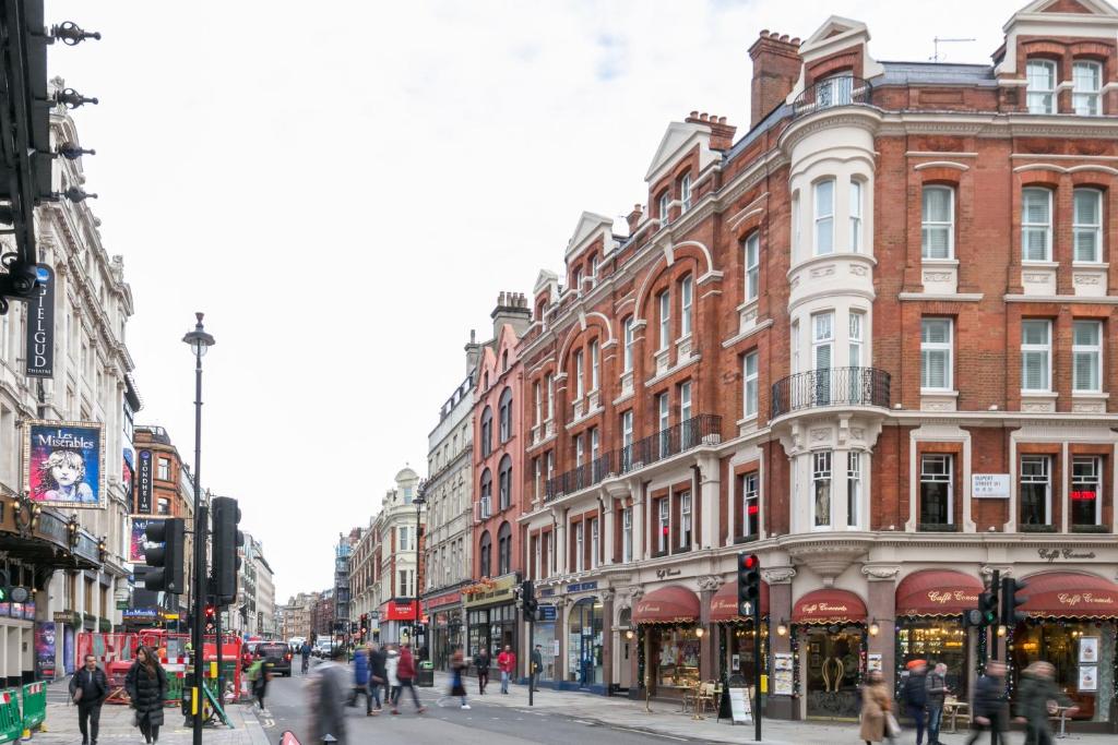 a busy city street with buildings and people walking on the street at Urban Chic - Shaftesbury in London