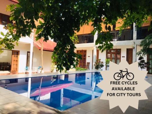 a swimming pool in front of a building with a bike on it at Kingcity Resort in Anuradhapura