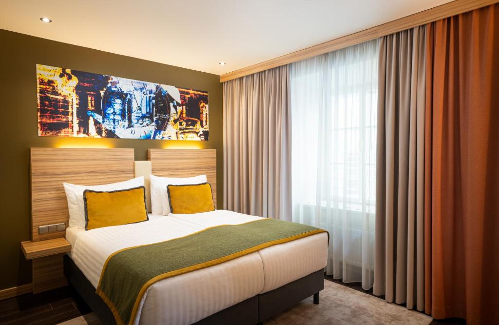 1 dormitorio con 1 cama grande con almohadas amarillas en Leonardo Boutique Hotel Salzburg Gablerbräu en Salzburgo