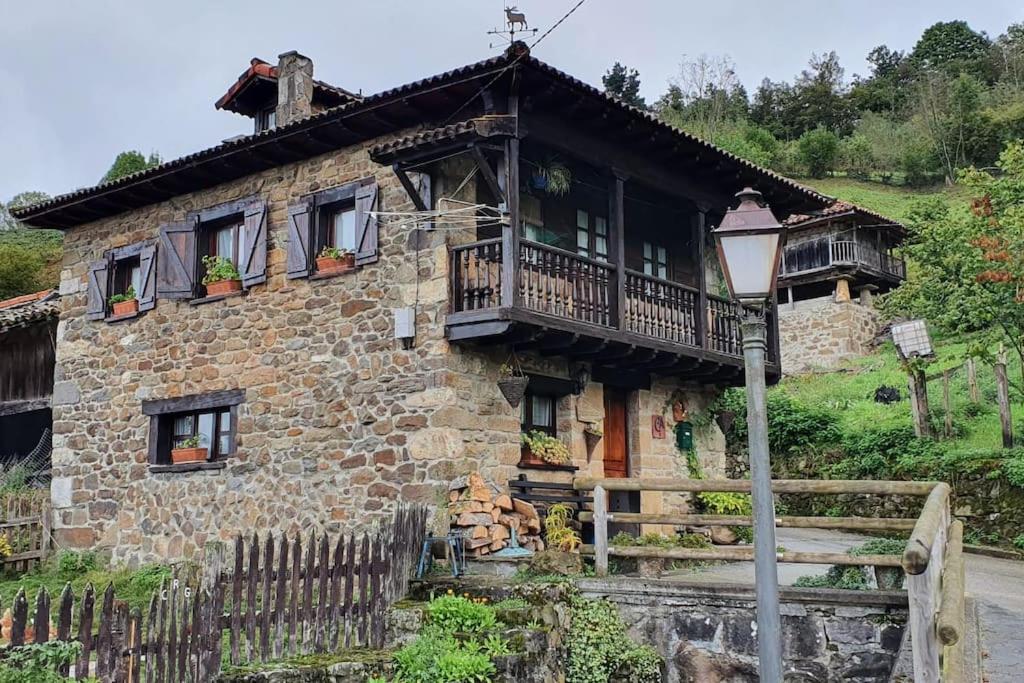 uma antiga casa de pedra com uma varanda e uma luz de rua em La Casa Rectoral de El Tozu em Caso