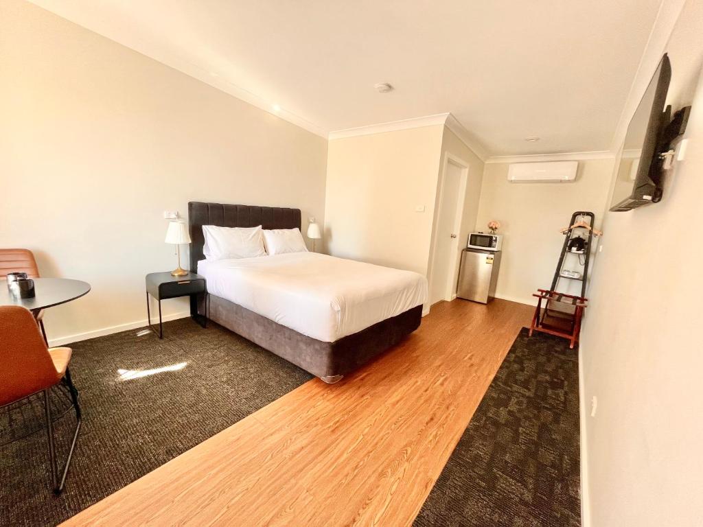 1 dormitorio con 1 cama, 1 mesa y 1 silla en Seven Inn, en Wagga Wagga