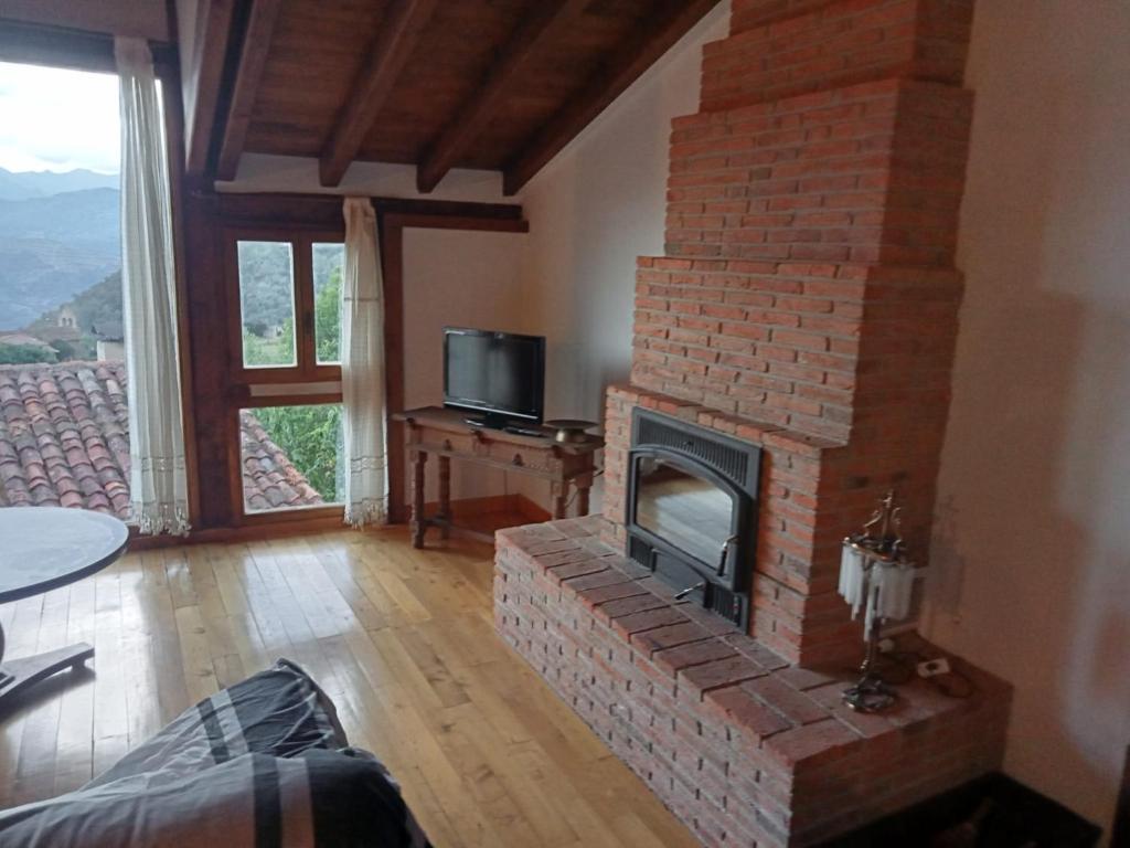 ein Wohnzimmer mit einem gemauerten Kamin und einem TV in der Unterkunft Casa Cahecho in Cahecho