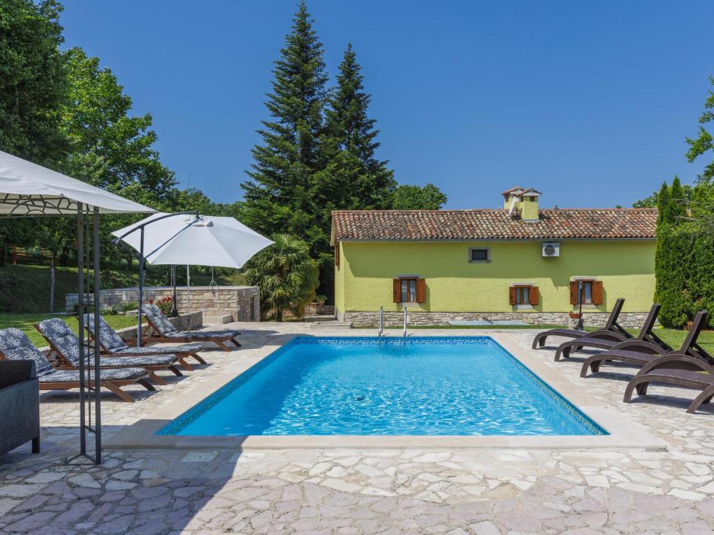 a pool with chairs and an umbrella and a house at Holiday Home Donada - LBN347 in Nedeščina