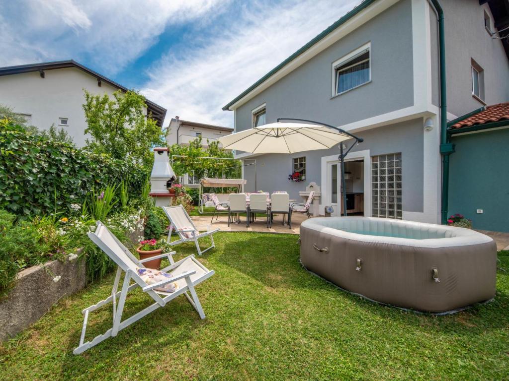 a backyard with a hot tub and chairs and an umbrella at Apartment Markulin by Interhome in Rubeši