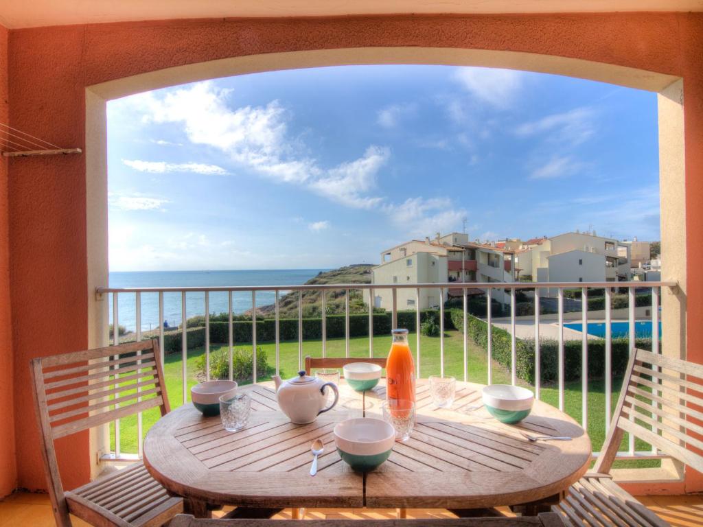 a wooden table on a balcony with a view of the ocean at Apartment Les Indes Galantes by Interhome in Cap d'Agde