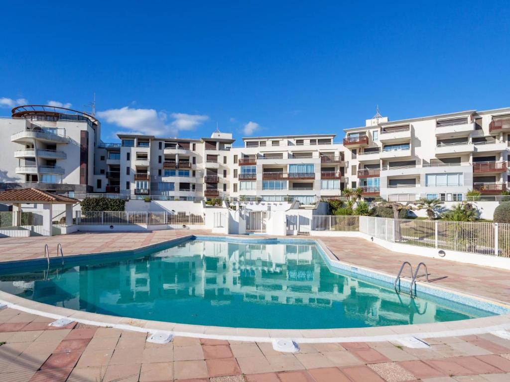 a swimming pool in front of some apartment buildings at Apartment Le Sunset-Cap Sud-1 by Interhome in Cap d'Agde