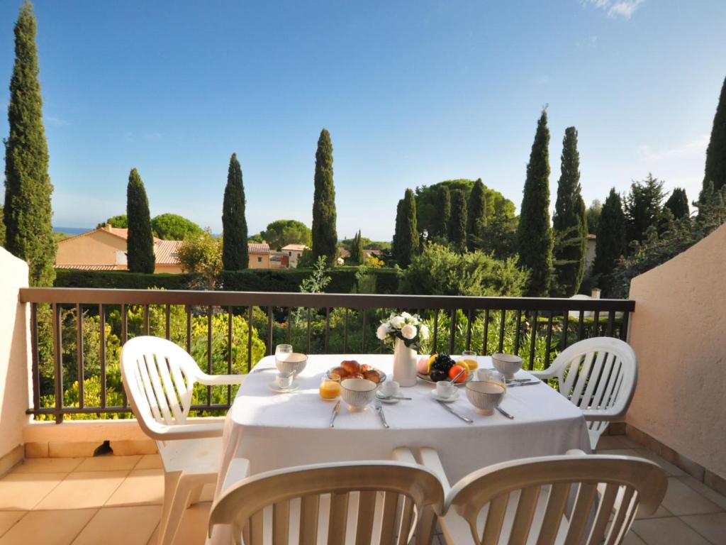 une table blanche avec des chaises sur un balcon arboré dans l'établissement Apartment les Oiseaux-1 by Interhome, à Cavalaire-sur-Mer