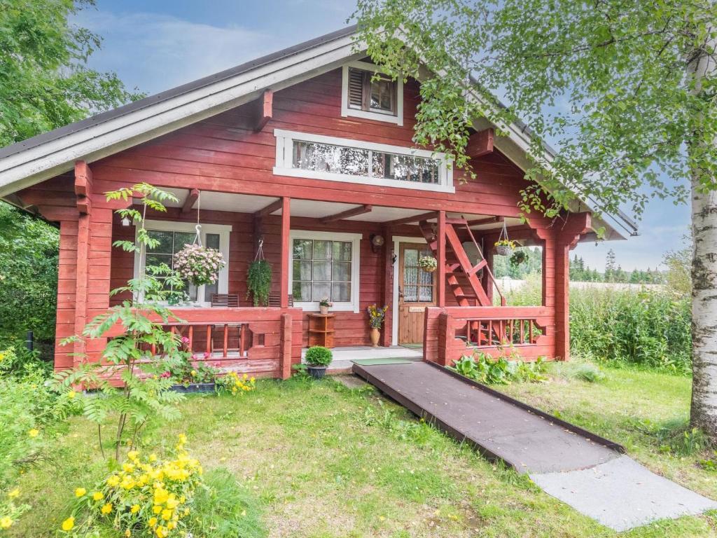 czerwony dom z gankiem i drzewem w obiekcie Holiday Home Tuomola by Interhome w mieście Lappajärvi