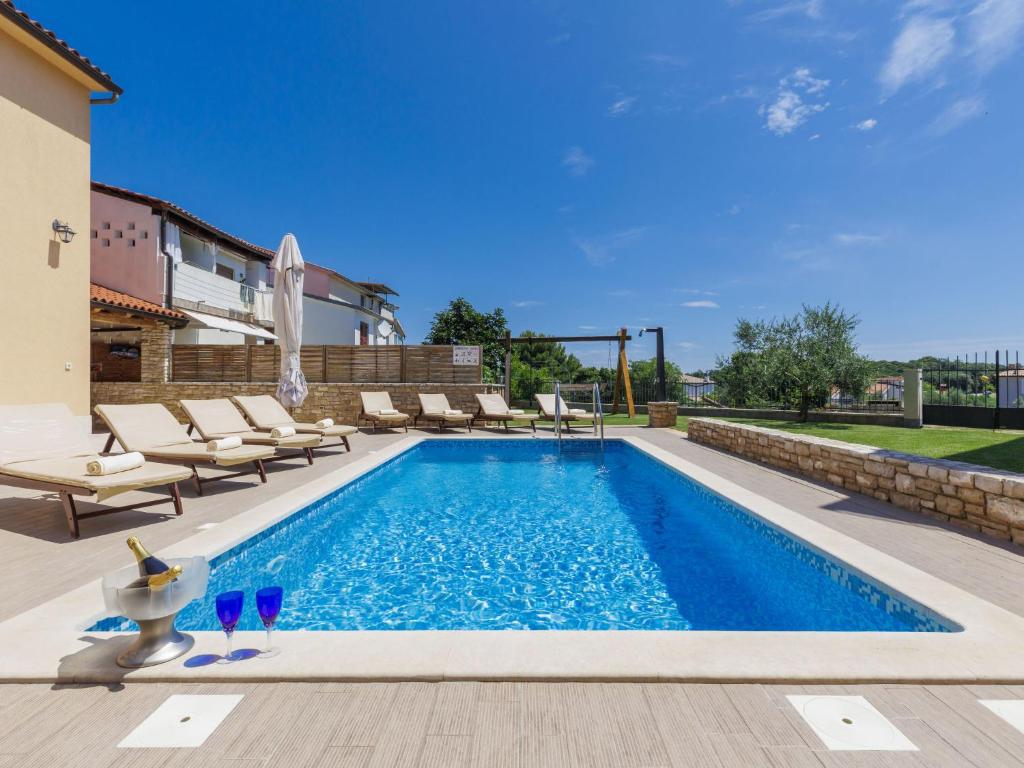 a swimming pool in a backyard with lounge chairs at Holiday Home Licardo by Interhome in Štinjan