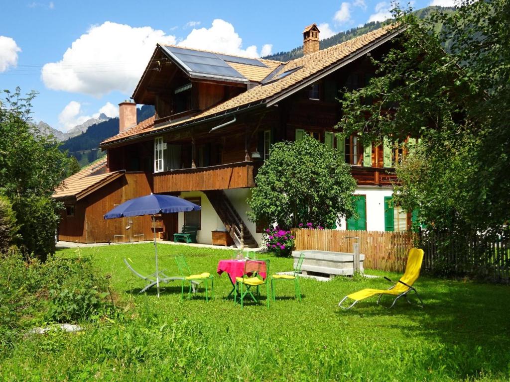 un cortile con sedie e ombrellone e una casa di Apartment Lischenhaus - Strubel by Interhome a Lenk