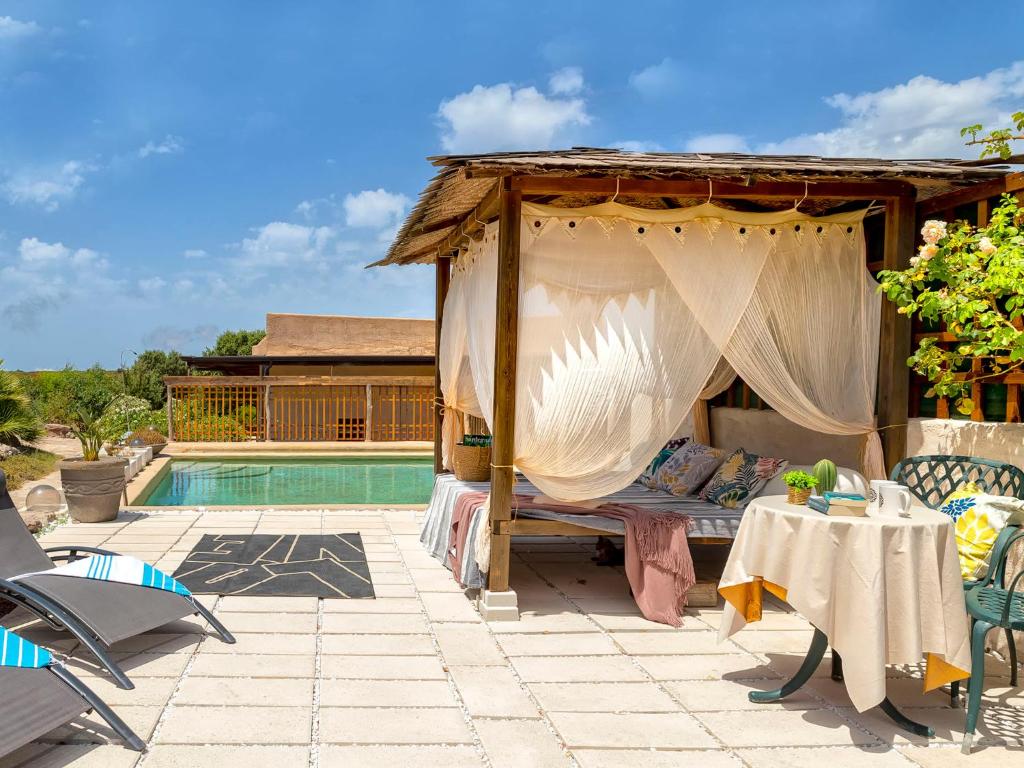 Villa Essenthia by Interhome في ألغيرو: سرير مظلة على فناء بجوار حمام سباحة