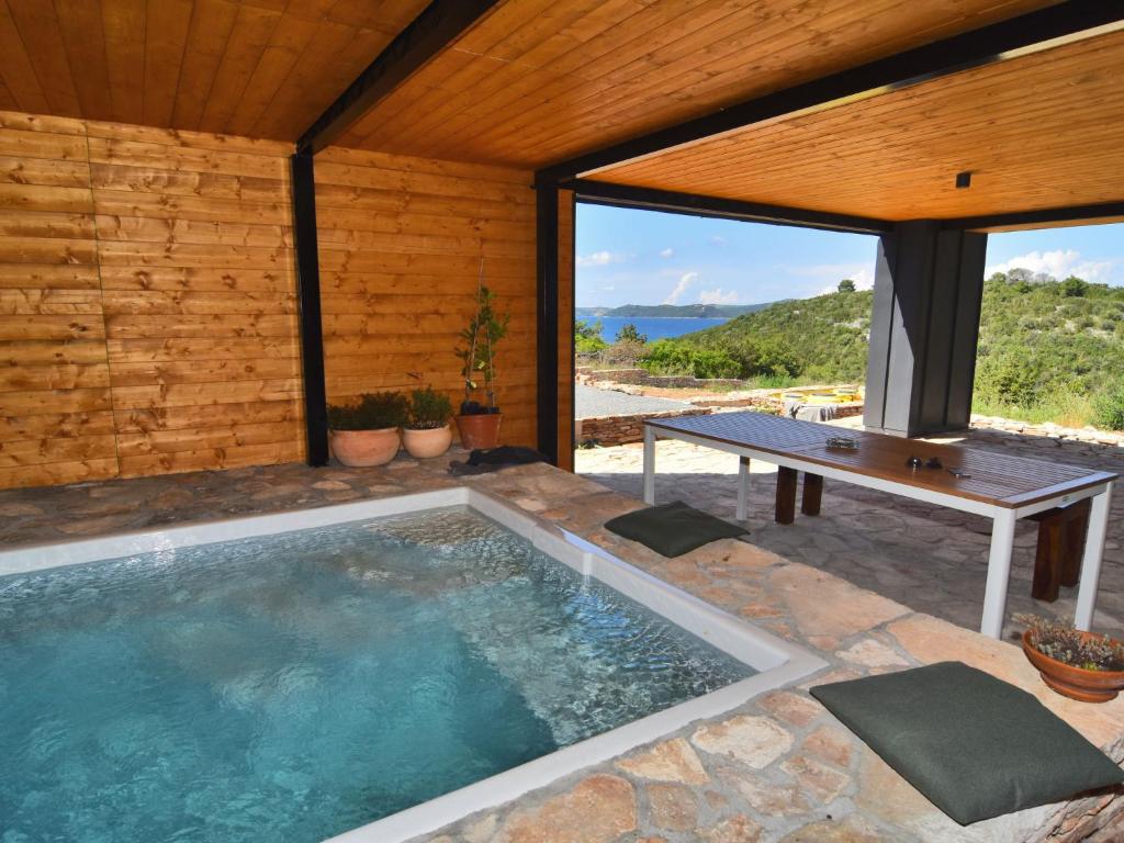 a swimming pool in a house with a table and a bench at Holiday Home Villa Baraka by Interhome in Božava