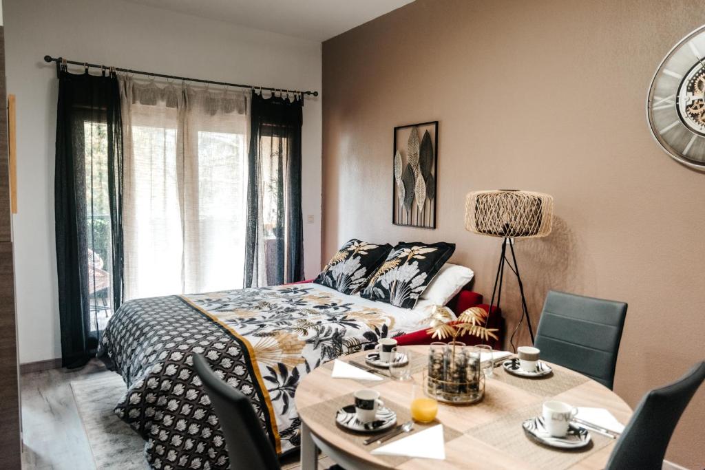 een slaapkamer met een bed en een tafel met stoelen bij Appartement moderne central avec piscine, garage privé et terrasse sud in Uzès