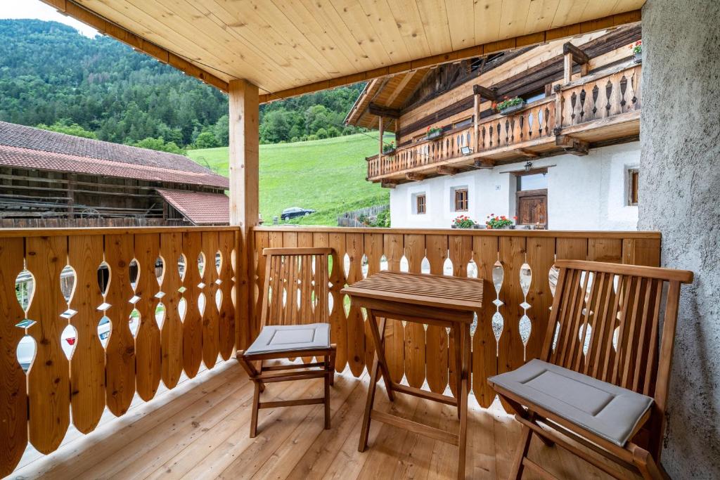 einen Holzbalkon mit 2 Stühlen und einem Tisch in der Unterkunft Apartement Lanthalerhof in Sankt Martin in Passeier