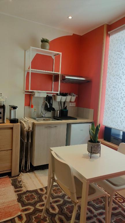 une cuisine aux murs rouges et une table avec des chaises dans l'établissement Studio rénové maison de village du Luberon, à Villelaure