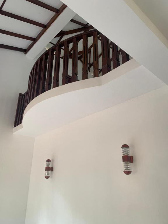 uma parede branca com uma escada de madeira num quarto em Aldea bleu em Midigama East
