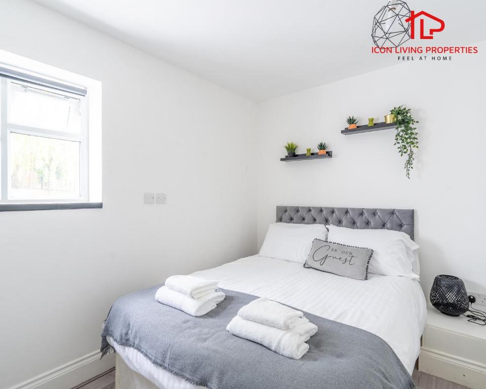 a white bedroom with a bed with towels on it at Arch-View Apartment 1 By Icon Living Properties Short Lets & Serviced Accommodation Wembley in London
