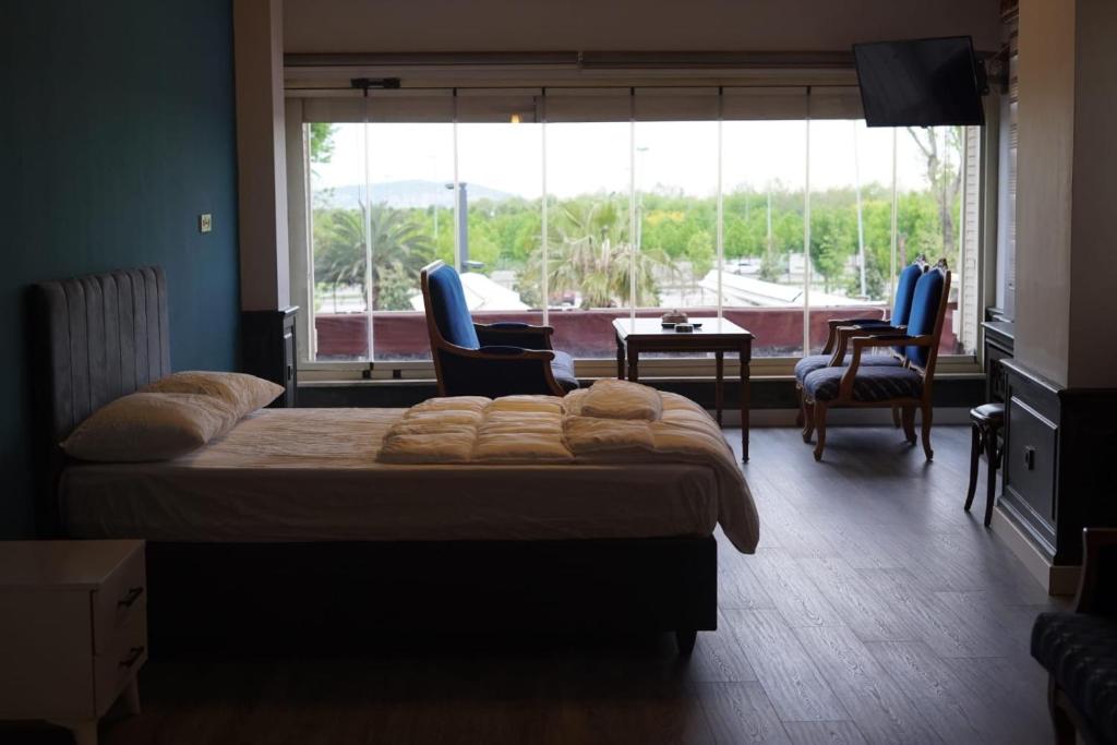a bedroom with a bed and chairs and a large window at Yalı Beach Houses in Istanbul