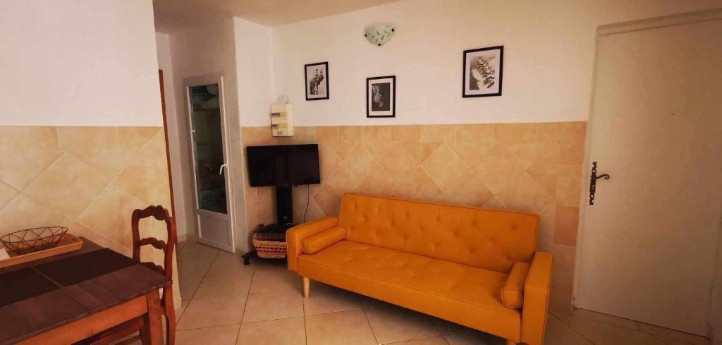 a living room with an orange couch and a tv at Villa les chênes in Bargemon