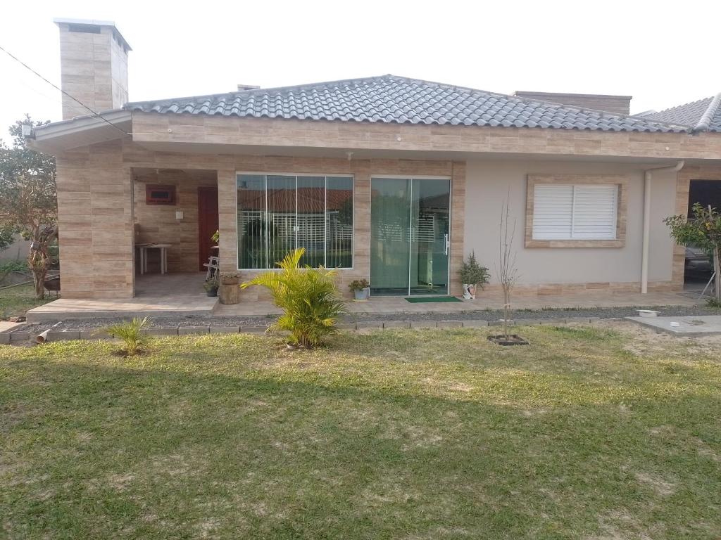 a house with a green door in a yard at Casa de Praia in Balneário Gaivotas