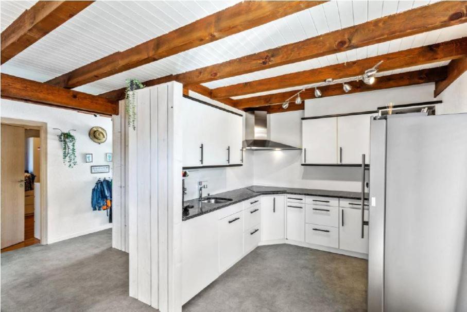 a kitchen with white cabinets and a refrigerator at Villa avec grand jardin, proche du centre-ville in Yverdon-les-Bains