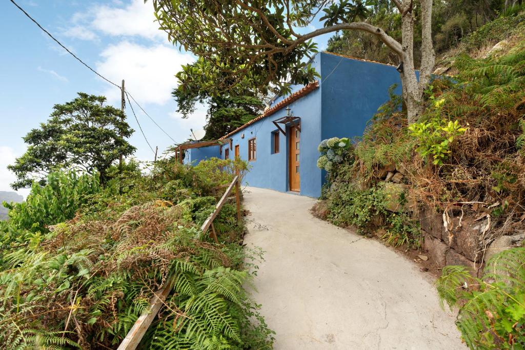 un bâtiment bleu sur une colline à côté d'un chemin de terre dans l'établissement Casa Azul del Roque Negro, à Santa Cruz de Tenerife