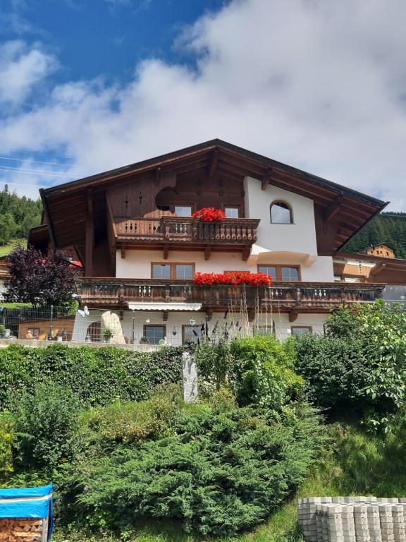 ein Gebäude mit roten Blumen auf dem Balkon in der Unterkunft Apartment Rahm in Gerlosberg