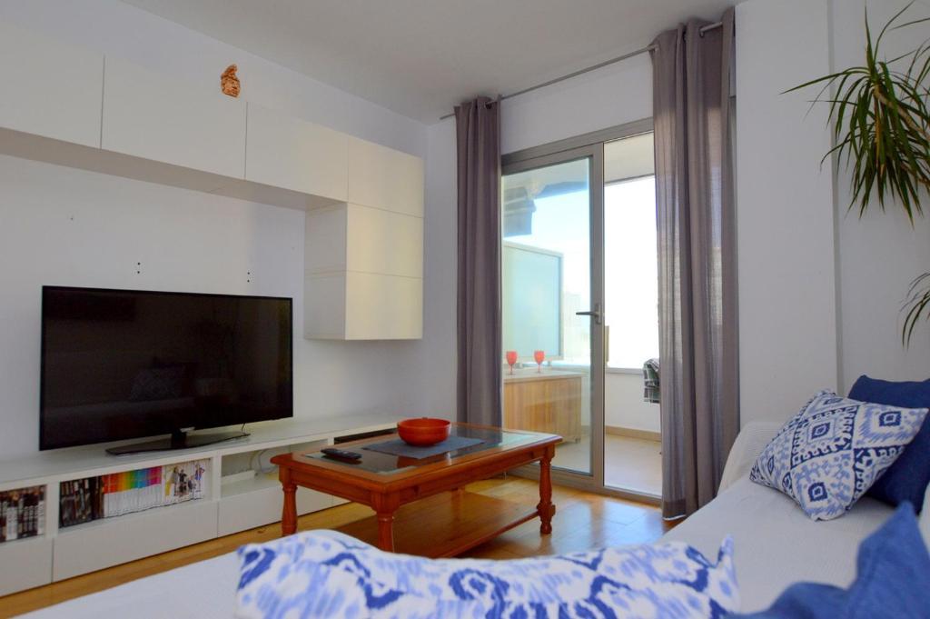 uma sala de estar com um sofá, uma televisão e uma mesa em Coqueto apartamento a pocos metros de playa em Can Pastilla