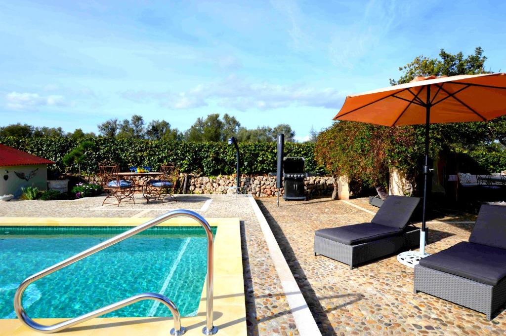 uma piscina com um guarda-sol e uma cadeira em Casa con piscina en bonito entorno Mia em Costitx