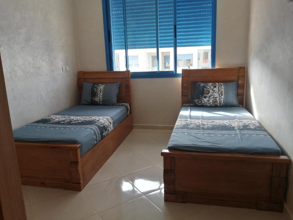 Duas camas num quarto com uma janela em Perla Andaloussia em Minaret de Mansuria