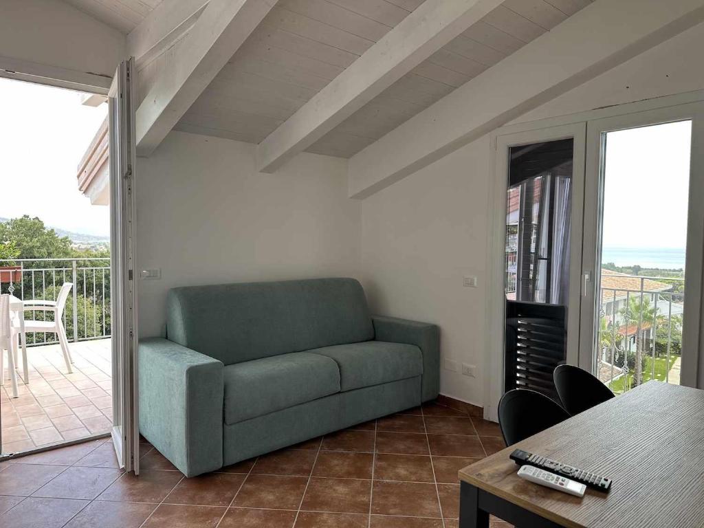 un sofá verde en una sala de estar con balcón en Appartamento Santa Lucia F, en Policastro Bussentino