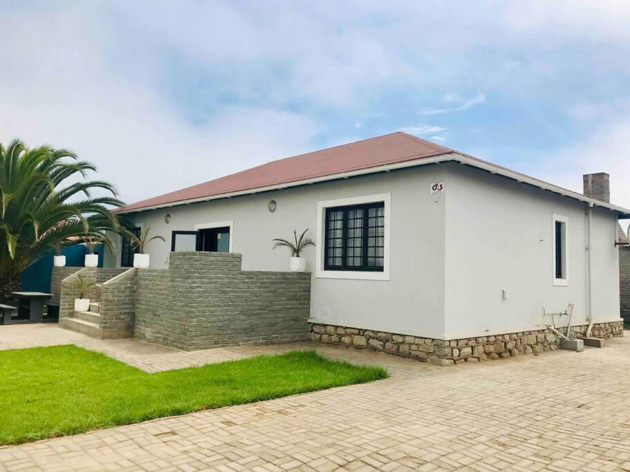 ein weißes Haus mit Ziegelwand und Gras in der Unterkunft 3 Bedroom, 3 Bathroom, Close to the Beach & Town in Swakopmund