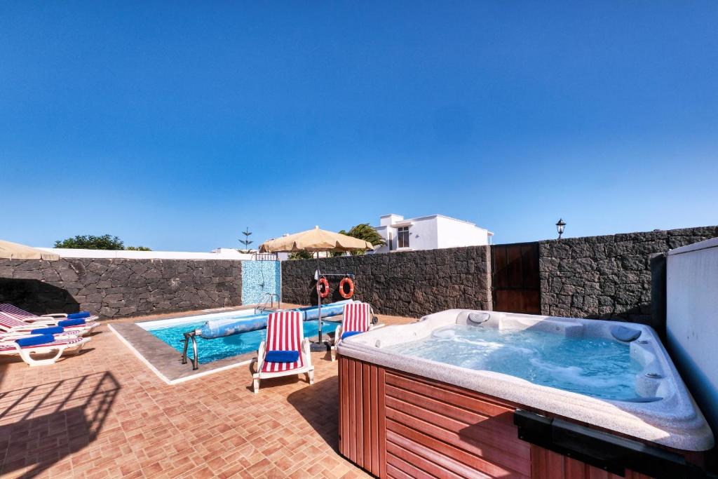 una vasca idromassaggio su un patio con sedie e piscina di Villa Aurelia-pool, jacuzzi and solarium a Playa Blanca