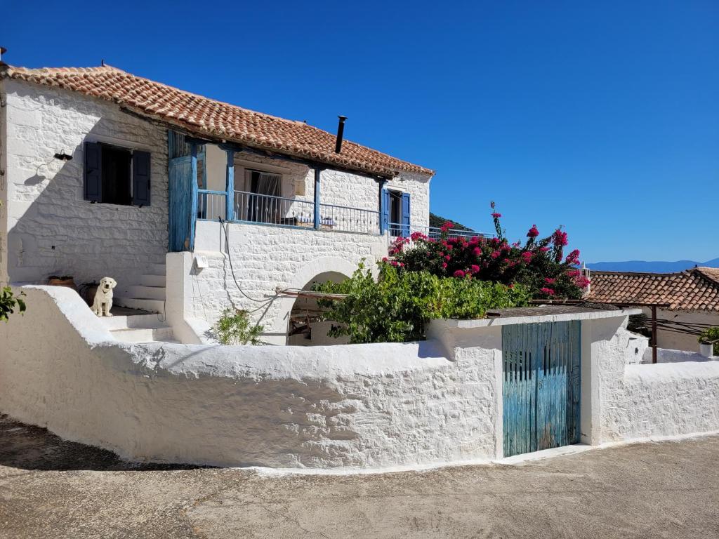 une maison blanche avec une porte bleue et des fleurs dans l'établissement Lovely traditionnal house with sea view, à Tyros