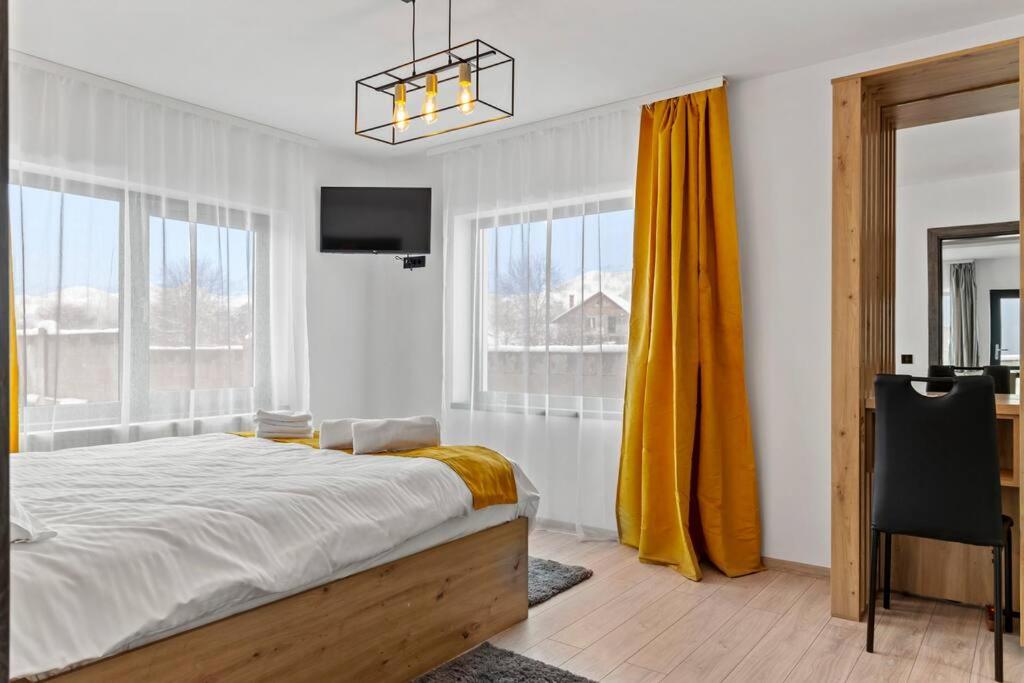 um quarto com uma cama, uma televisão e janelas em D&M Family Residence Bran 2 em Bran