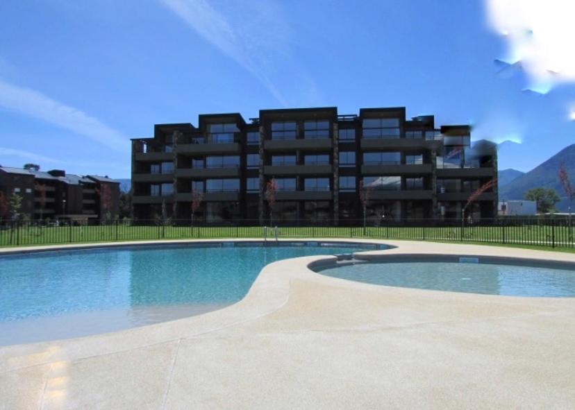 a large swimming pool in front of a building at Departamento Condominio Costa Pucon in Pucón