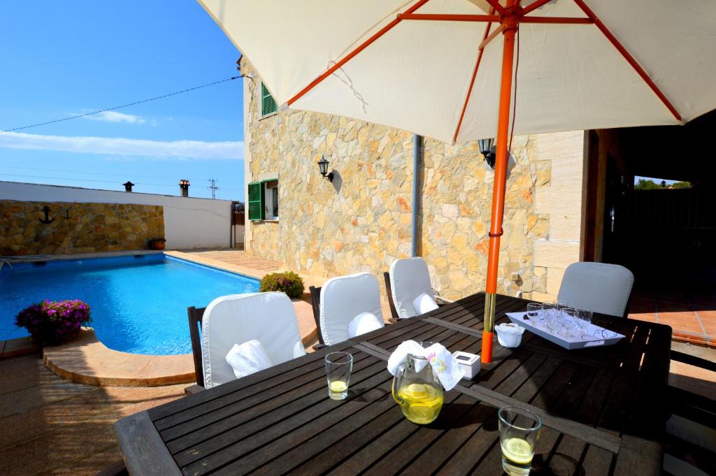 a table with an umbrella next to a swimming pool at Bonito chalet con piscina cerca del mar in Can Pastilla