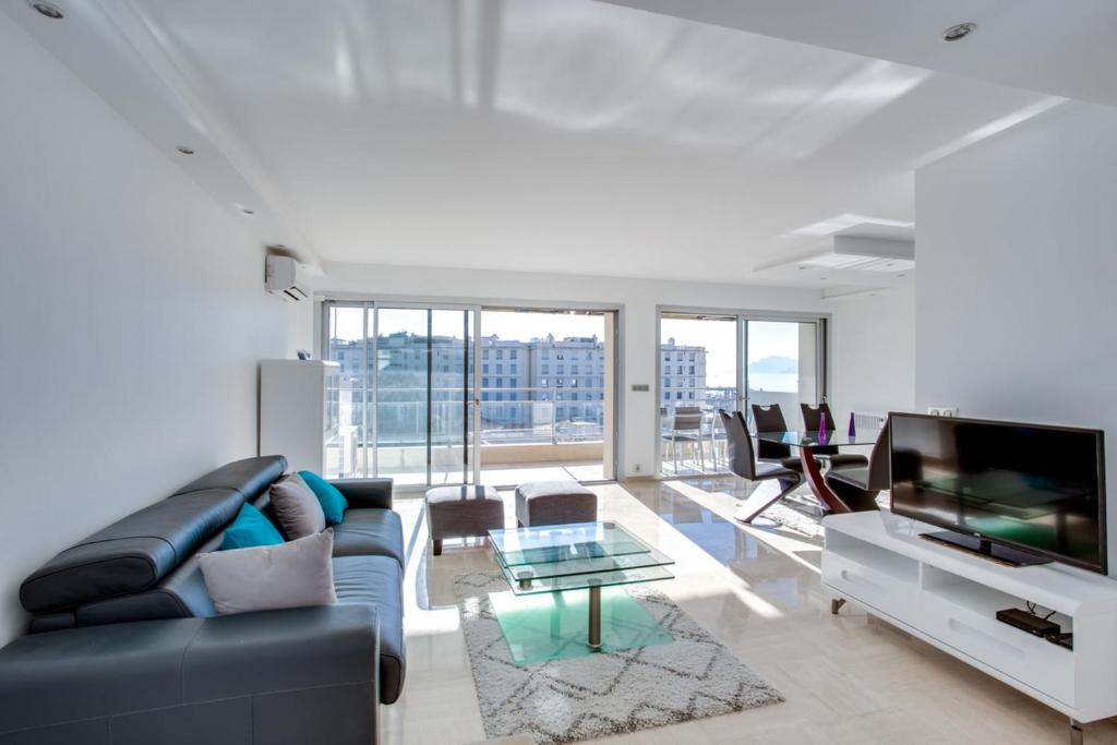 un salon avec un canapé et une télévision dans l'établissement Appartement Alexandre lumineux avec superbe vue mer, à Cannes