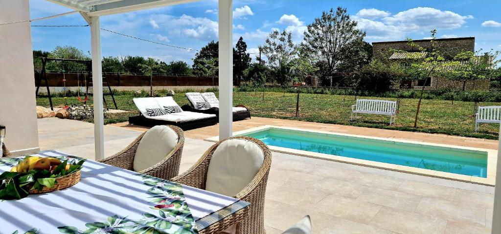 eine Terrasse mit einem Tisch, Stühlen und einem Pool in der Unterkunft Agradable finca en un entorno natural in Lloseta