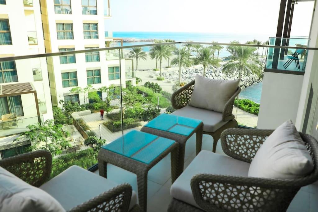 a balcony with chairs and tables and a view of the beach at Address Resort Apartments Fujairah - 2 bedroom apartment in Fujairah