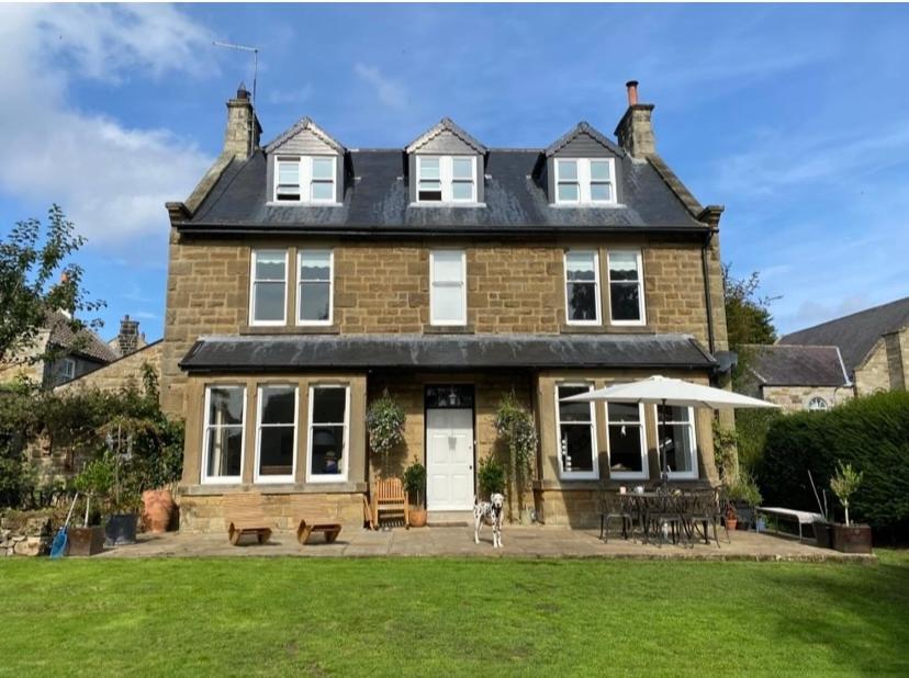 een groot bakstenen huis met een hond ervoor bij Floyter House North Yorkshire Moors National Park in Danby