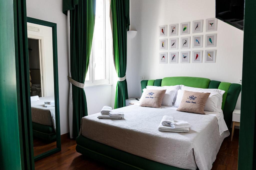 a bedroom with a bed with green curtains and a mirror at Residenza Romana in Rome