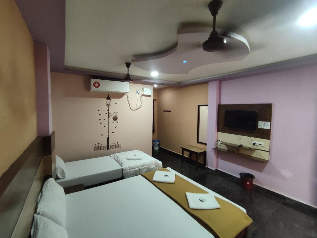 um quarto de hotel com duas camas e uma televisão de ecrã plano em sri Murugan beach paradise hotel em Mahabalipuram